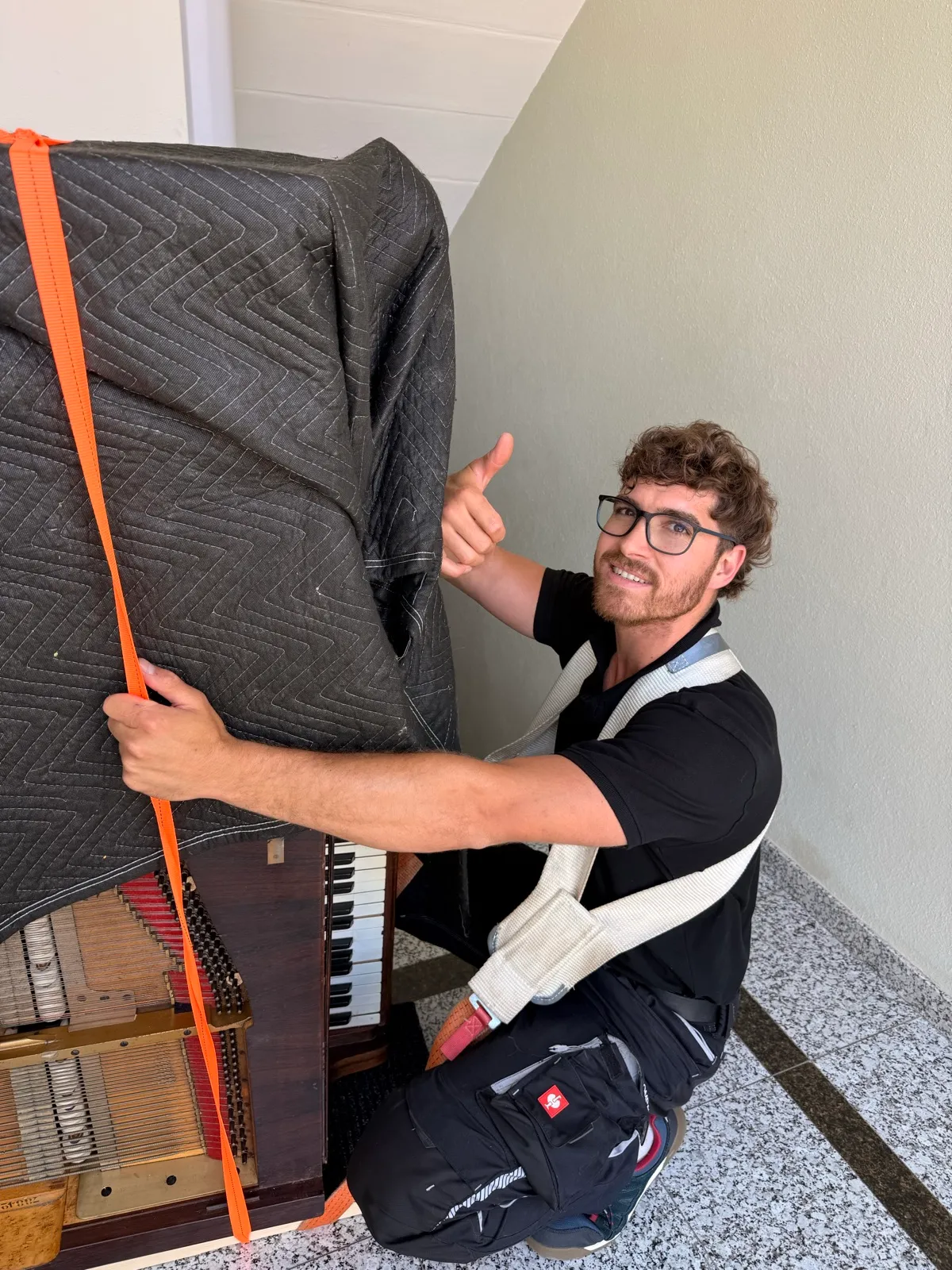 Un déménageur sangle un piano
