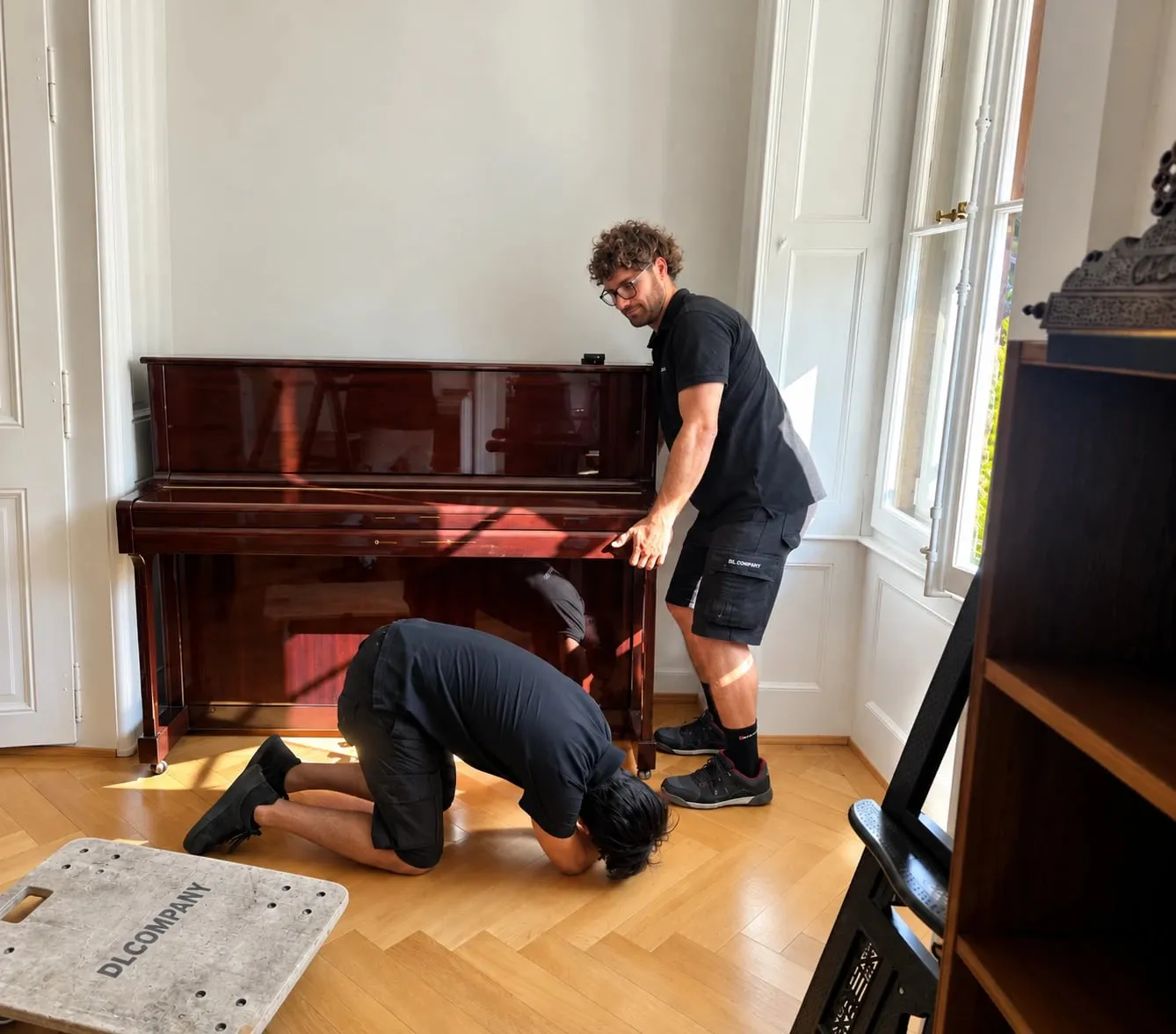 Deux déménageurs préparent un piano droit