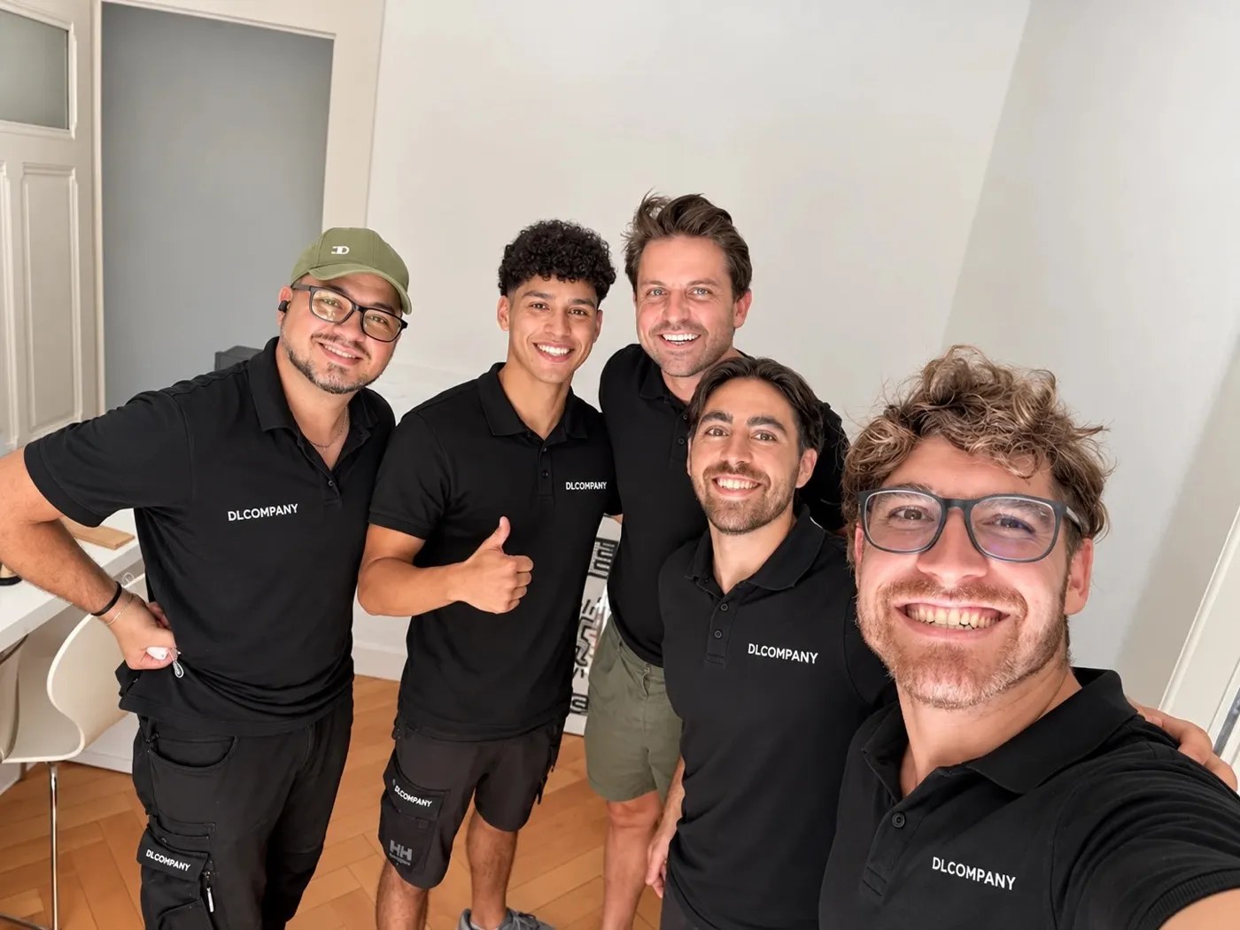 Selfie de l’équipe DL Company avec cinq déménageurs en polo noir dans un appartement